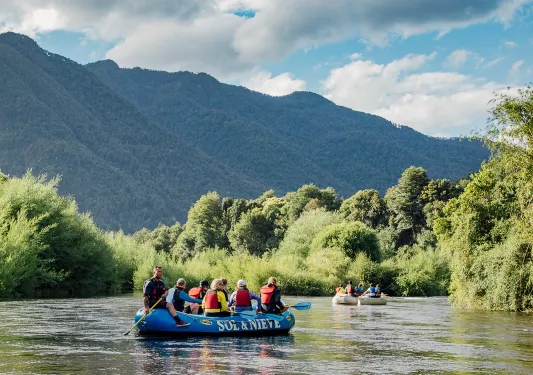 Group of people on a blue raft, paddling in the middle of a river