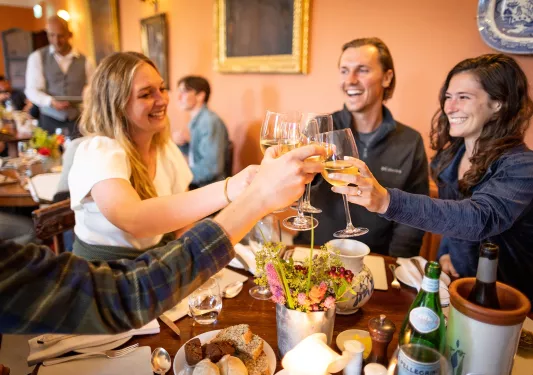 Group of people at a dining table raising their wine glasses
