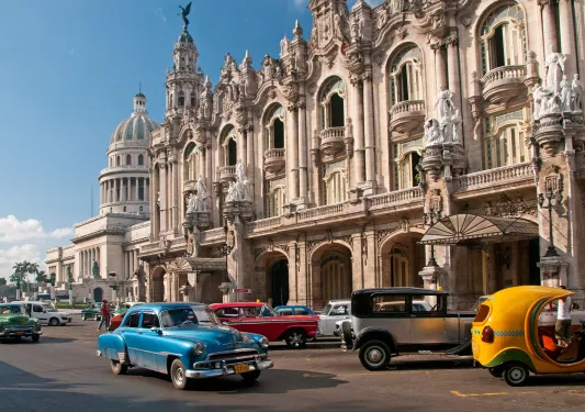 Exterior view of large palace building with old school cars in front