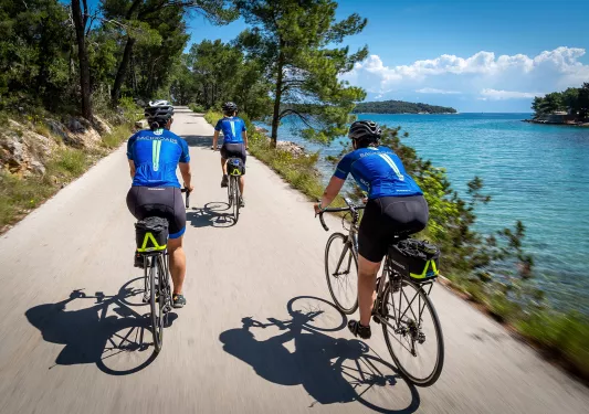 Group of people riding bikes on a path, with the ocean to the right