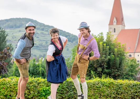 Two men and one woman wearing traditional Dutch clothing, smiling with hands on their hips