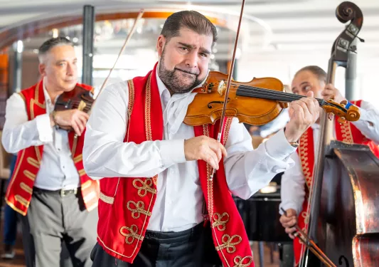 Two men playing the violin and one one playing the cello