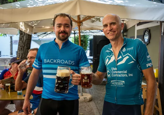 Two men smiling while holding up large beer mugs