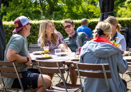 Group of people smiling while sitting down at an outdoor dining table