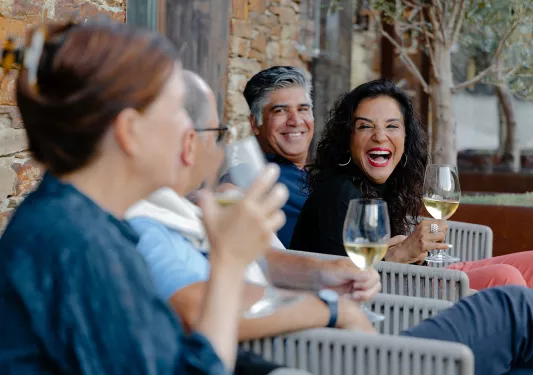 Group of people smiling and laughing while holding wine glasses