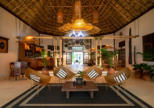 Large bar and lounge with straw chairs and a wooden table in the center