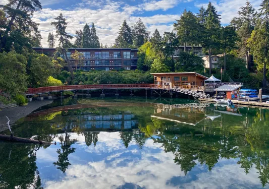 Exterior view of large hotel building with a lake and wooden bridge in front