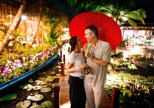 Man and woman hugging and looking at each other under a red umbrella