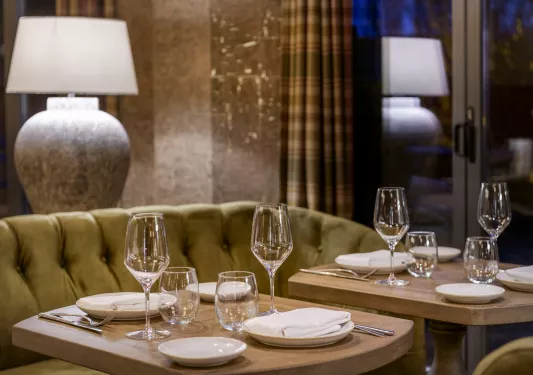 Two small tables with plates and handkerchiefs, with glasses on wine