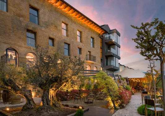 Exterior view of brick, multi-story building with a garden patio in front