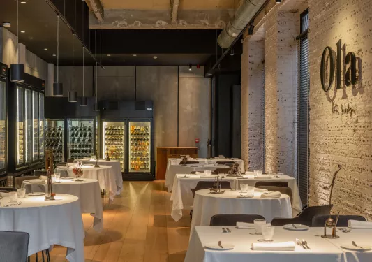Indoor dining hall with circular, white dining tables and stone walls