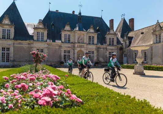 Group of people riding bikes in front of a castle building