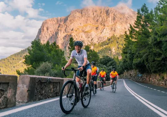 Group of people riding bikes along a road with large mountains in the background