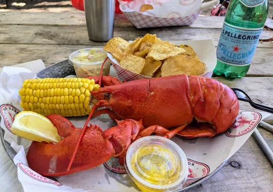 Plate with a boiled lobster, a half of corn and a plate of chips