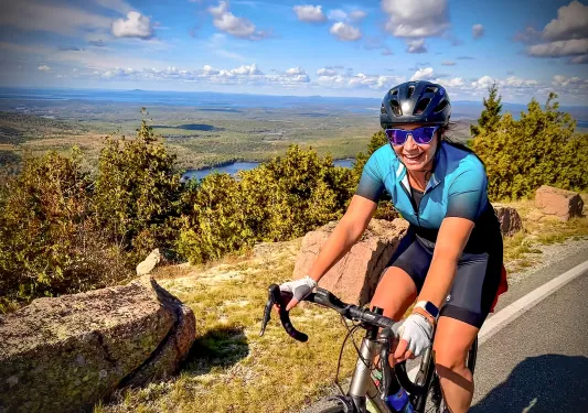 Woman wearing biking gear, smiling and riding her bike