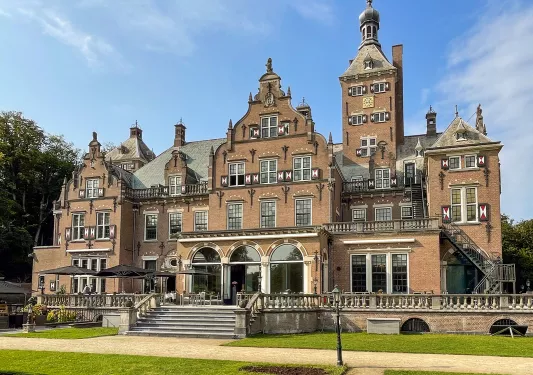 Exterior view of large brown hotel building with a large patio in front