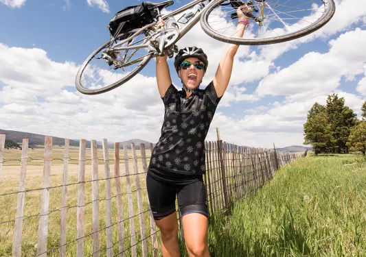 Woman smiling while carrying her bike above her head