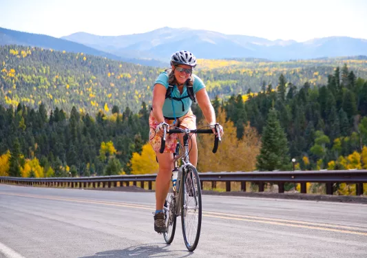 Woman smiling while riding a bike, with a forest in the distance