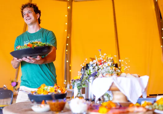 Man smiling while holding a large salad bowl