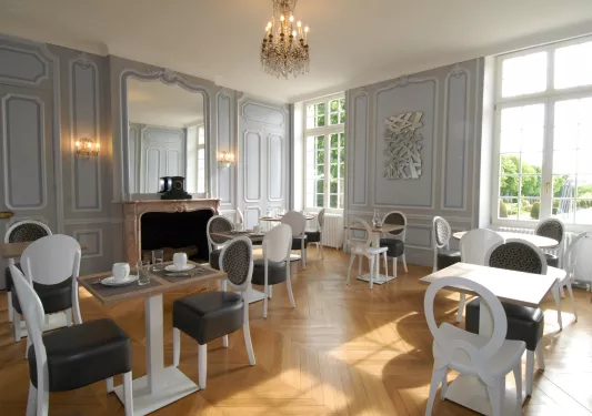Room with wooden flooring and black and white chairs, with a small chandelier from the ceiling