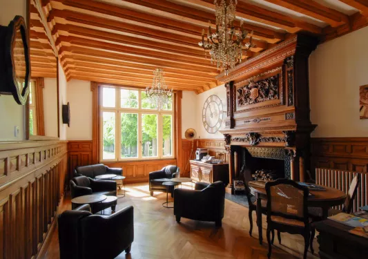 Lounge room with wooden fireplace and large, leather chairs