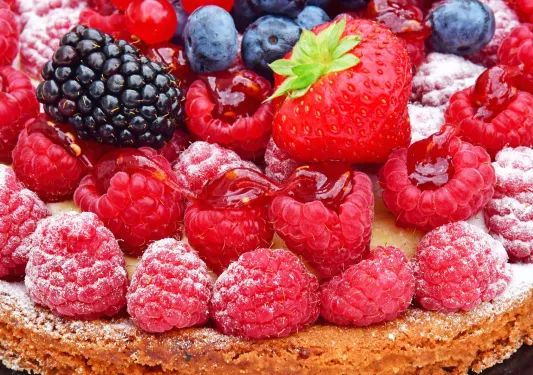 Pastry with a pile of raspberries, blackberries and blueberries on top