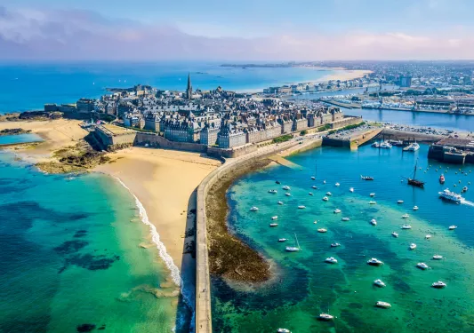 Rustic town with castle-like buildings, surrounded by a clear ocean