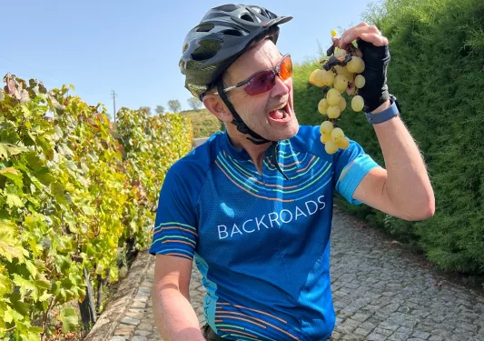 Man riding a bike while hoping up a vine of grapes