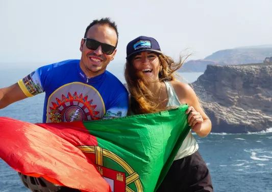Man and woman smiling while holding up a Portugal flag
