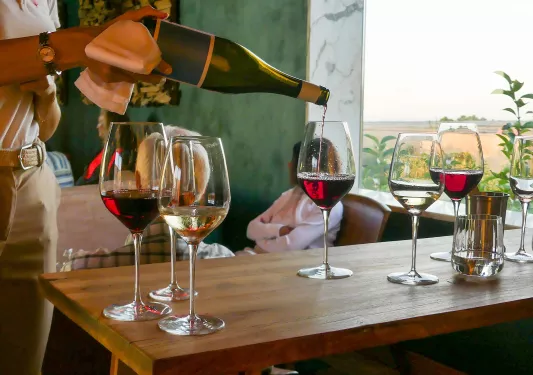 Person pouring a bottle of wine into wine glasses