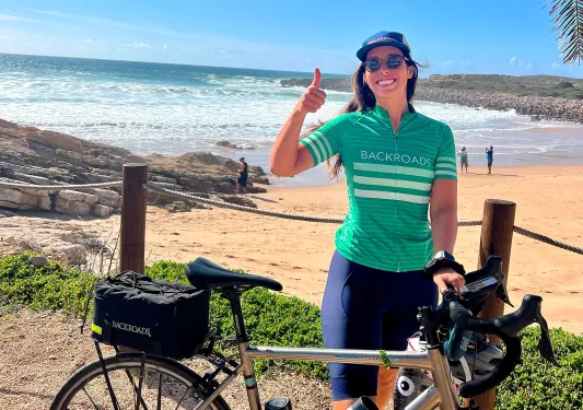 Woman standing next to a bike, smiling with her thumb up