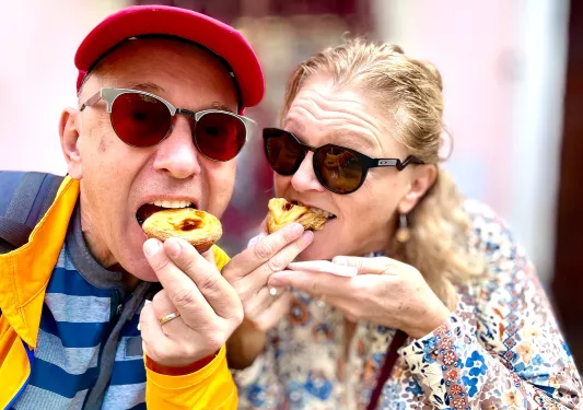 Man and woman eating a pastry and smiling