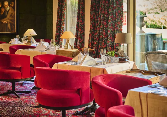 Dining area with beige, square tables and red, cushioned chairs