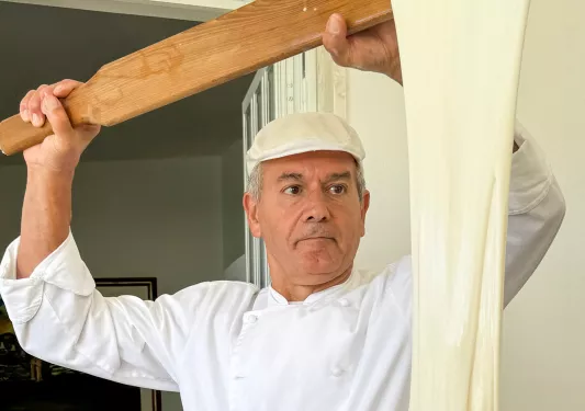 Man with a large paddle making very stretchy cheese