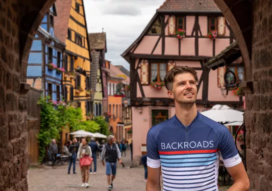 Man wearing a Backroads jersey, standing under a stone archway