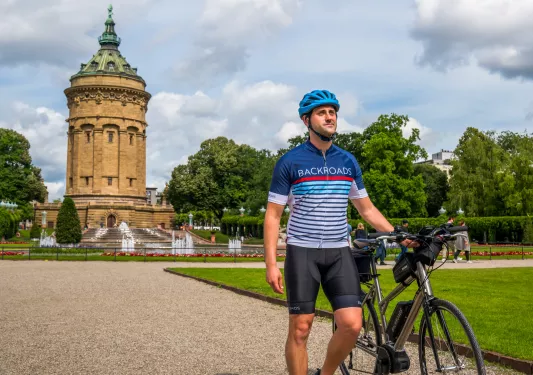 Man walking next to a bike, with a large castle-like building in the background