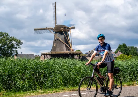 Man riding a bike with a windmill in the background