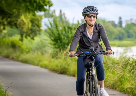 Woman riding a bike on a road, with a lake in the background