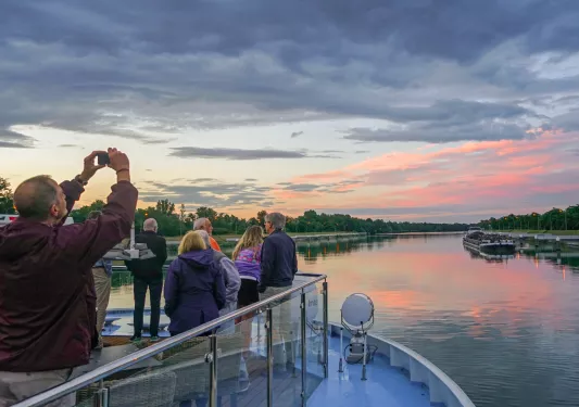 Group of people on a glass ledge looking at a sunset