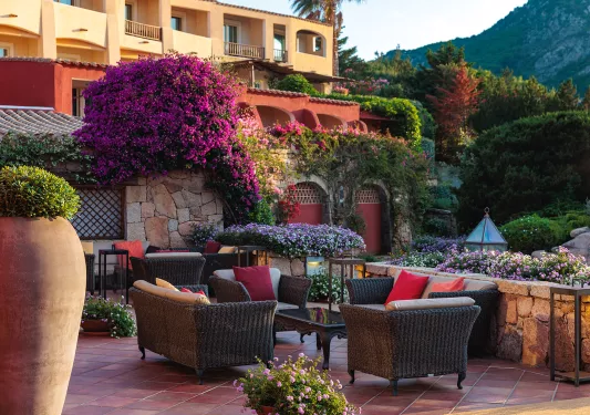 Outdoor patio with woven, cushioned chairs with a garden in the background