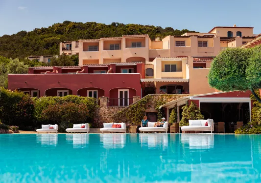 Outdoor pool with large beige and brown hotel buildings in the background