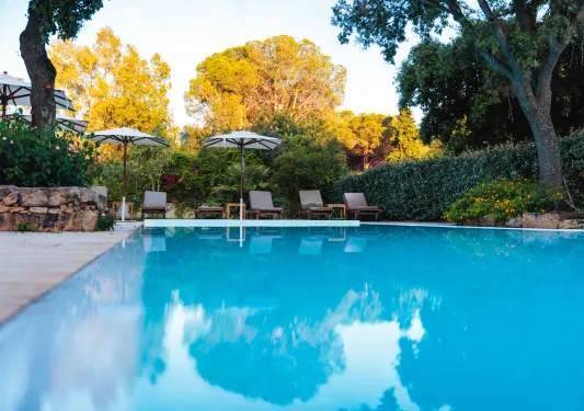 Outdoor pool with gray reclining chairs and umbrellas