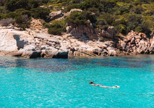 Woman snorkeling in a lake with a large cliff in the background