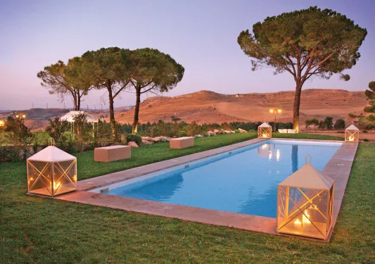 Outdoor pool, surrounded by tall trees and hills in the distance