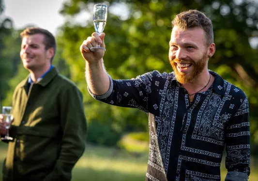 Two men smiling while holding up glasses of champagne