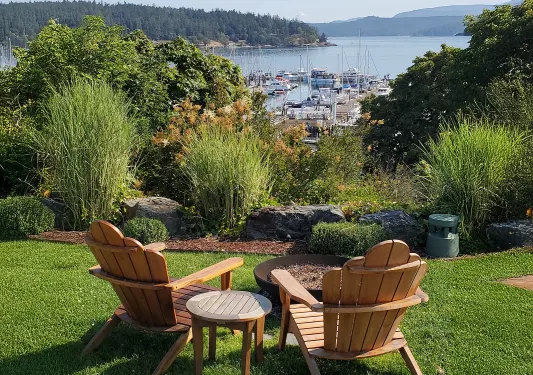 Two wooden chairs in an outdoor garden, overlooking boats and a large lake