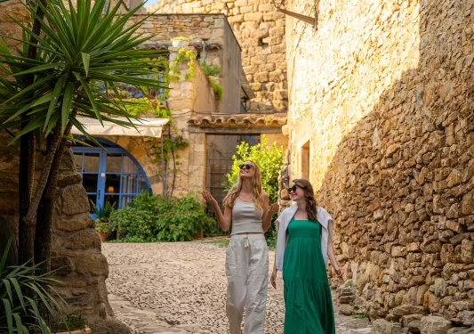 Two women smiling while walking through a stone alleyway