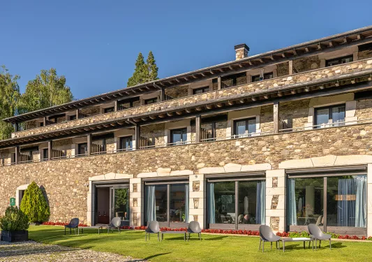 Exterior view of stone building with large windows and a grass area in front