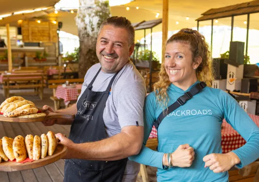 Woman smiling with a man wearing an apron, holding two plated full of baked bread