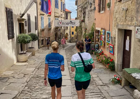 Two women walking in an alleyway surrounded by stone buildings